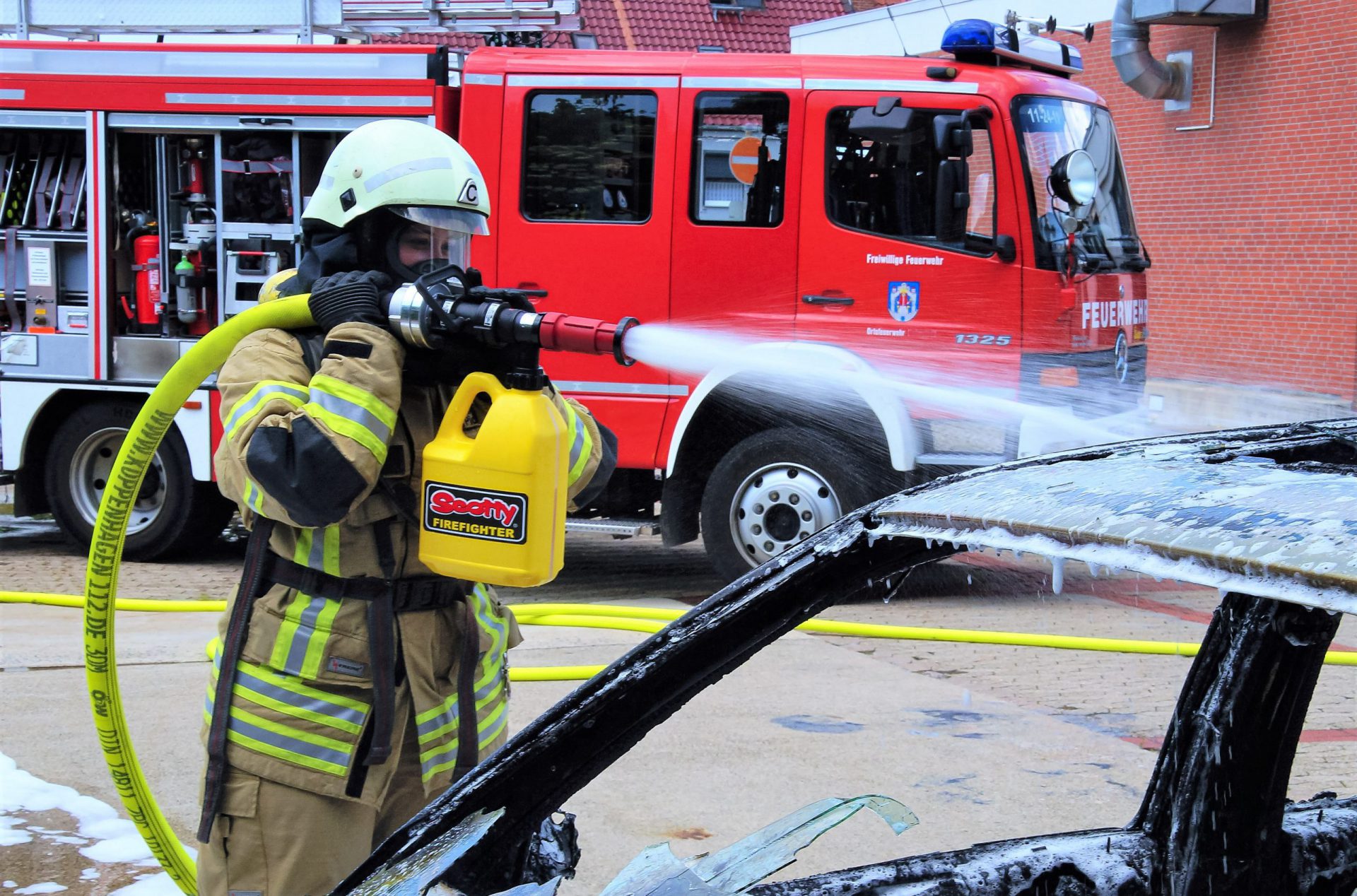 Ein Feuerwehrmann, welcher mit einem Scotty Firefighter Schaumrohr inkl. Schaumkanister einen Pkw Brand löscht